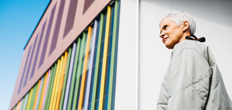 Older woman next to a colorful building